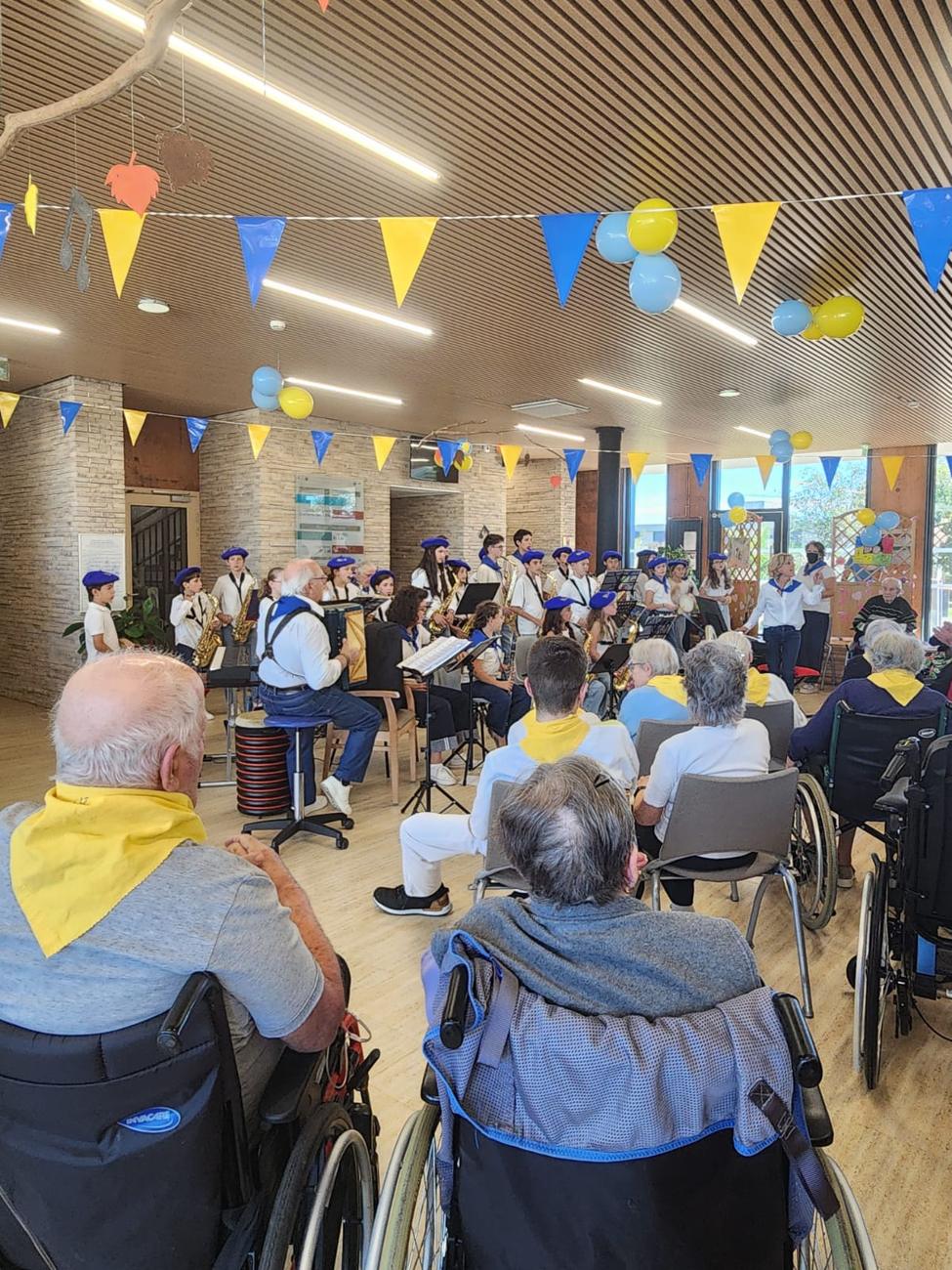 Les Muse's Kids jouent devant les résidents, salle décorée de fanions bleus et jaunes